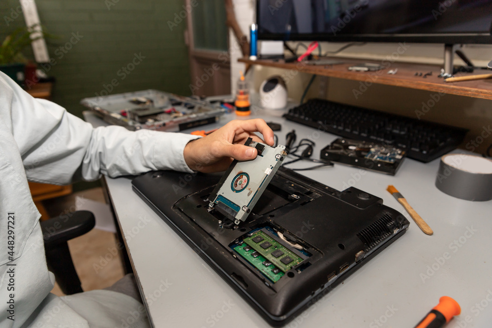 technician disassembling a damaged laptop