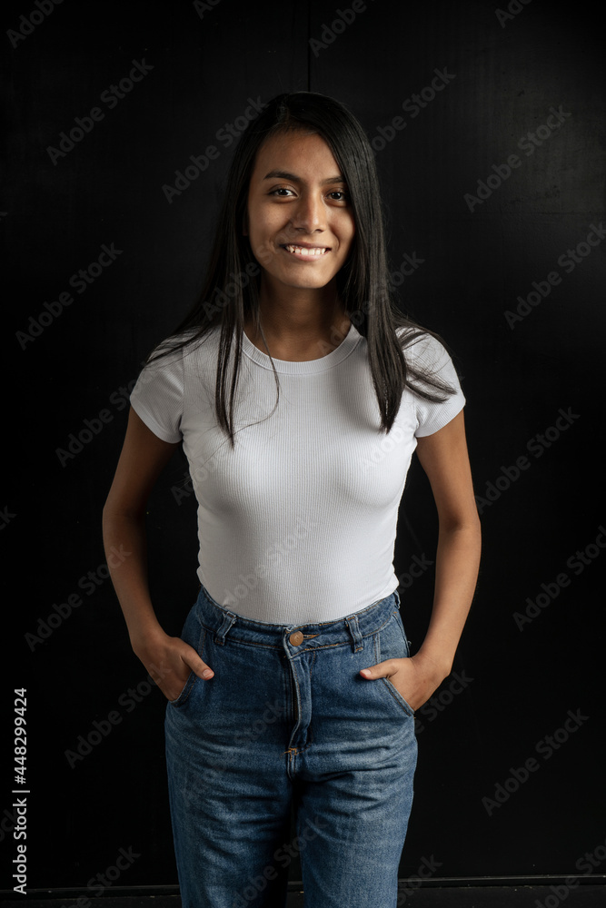 American shot of a beautiful smiling Latin woman with a white shirt and tame in her pockets on a black background. American shot of a beautiful smiling Latin woman with a white shirt and tame in her pockets on a black background.
