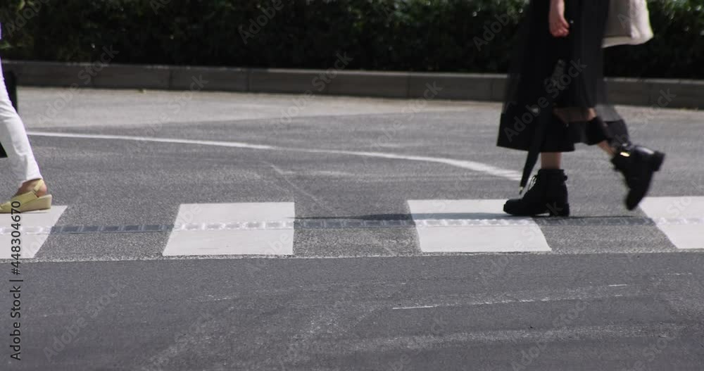 A slow motion of body parts of walking people on the crossing at the business town