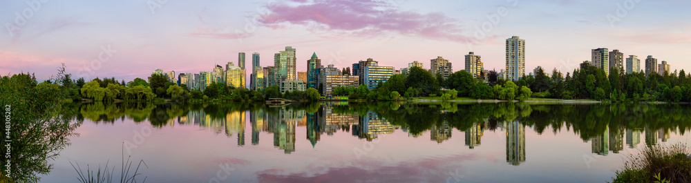 Panoramic View of Lost Lagoon in famous Stanley Park in a modern city with buildings skyline in background. Colorful Sunset Sky. Downtown Vancouver, British Columbia, Canada.