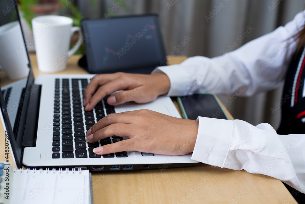 Young woman sitting, using laptop, tablet, notebook and calculator working from home. Closeup shot of unrecognizable woman, hands working on computer keyboard. Young woman sitting, using laptop, tablet, notebook and calculator working from home. Closeup shot of unrecognizable woman, hands working on computer keyboard.
