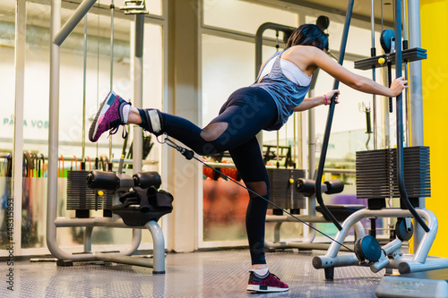 Photos young hispanic latina doing gluteus with kickbacks in a rope machine