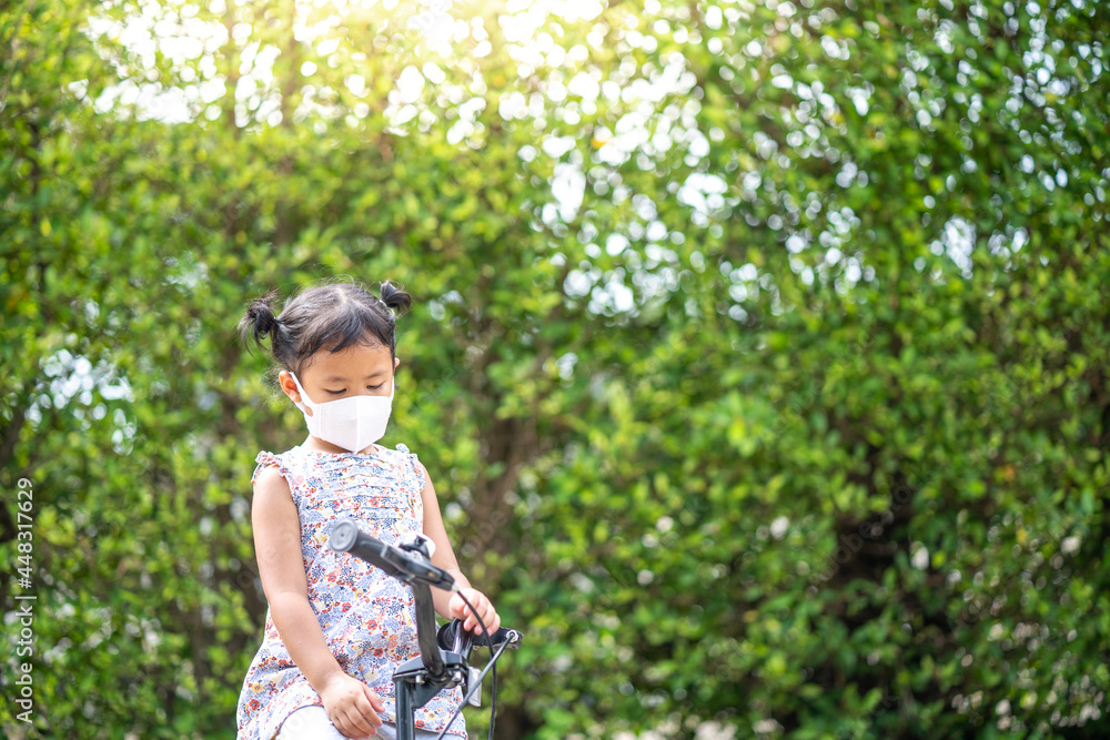 Cute small girl with protective face mask on bicycle outdoor. Cute small girl with protective face mask on bicycle outdoor.