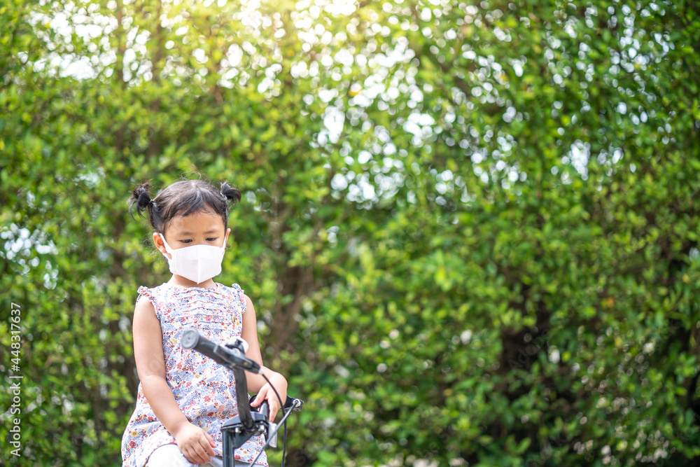 Cute small girl with protective face mask on bicycle outdoor. Cute small girl with protective face mask on bicycle outdoor.