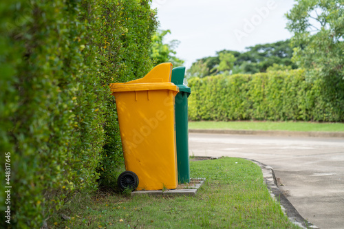 Standing yellow and green garbage bin at field.