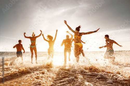 Big group of friends run and jump at sunset sea beach. Summertime holidays concept © cppzone