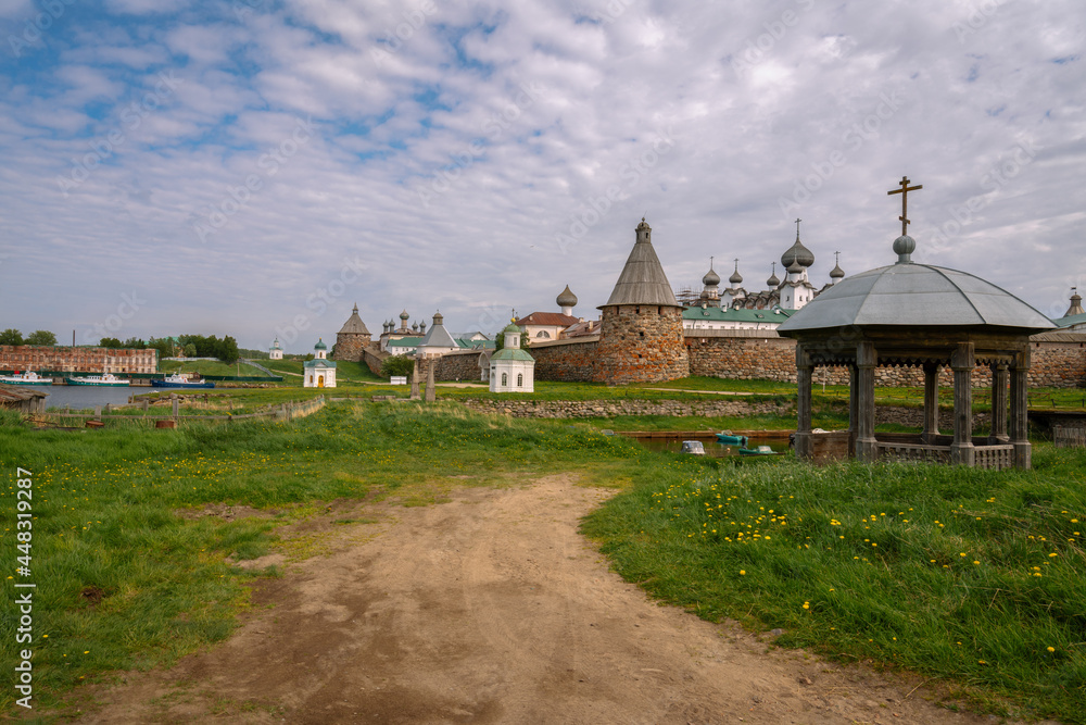 View of the ancient chapel-gazebo in the village Solovetsky and the Spaso-Preobrazhensky Solovetsky Monastery in the background on a sunny summer day, Solovetsky Island, Arkhangelsk region, Russia