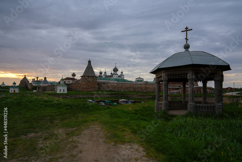 View of the ancient chapel-gazebo in the village Solovetsky and the Spaso-Preobrazhensky Solovetsky Monastery in the background on a cloudy summer evening, Solovetsky Island, Arkhangelsk region Russia