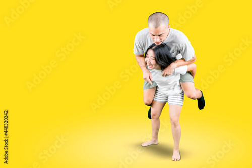 Fototapeta Woman giving her boyfriend piggyback ride on studio