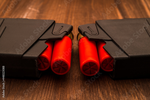 Two magazines with red cartridges 12 gauge lie opposite each other on the wooden table. Close up view