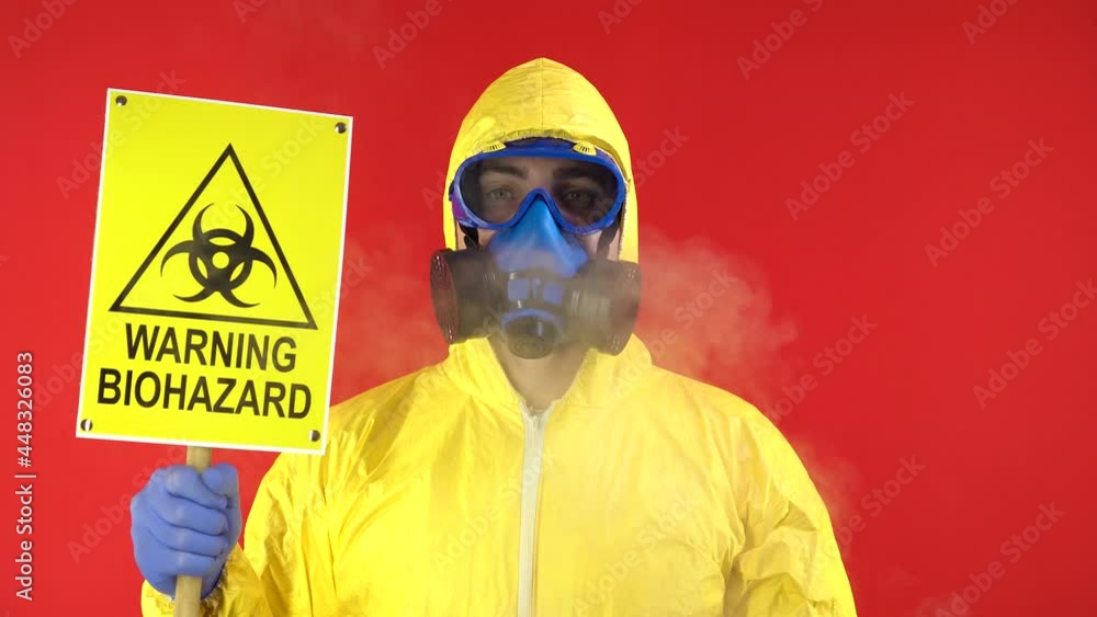 Man in Protective Chemical Suit, Mask and Banner in Hands. Biological Protection. Smoke Around Man. Protection Concept, Radioactive Hazard Concept. Red background, isolate, studio footage, 4k Man in Protective Chemical Suit, Mask and Banner in Hands. Biological Protection. Smoke Around Man. Protection Concept, Radioactive Hazard Concept. Red background, isolate, studio footage, 4k