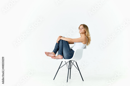 woman sitting on white chair with bent legs emotions lifestyle light background