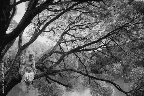 springtime dreaming female girl sitting on a tree branch, spring forest park