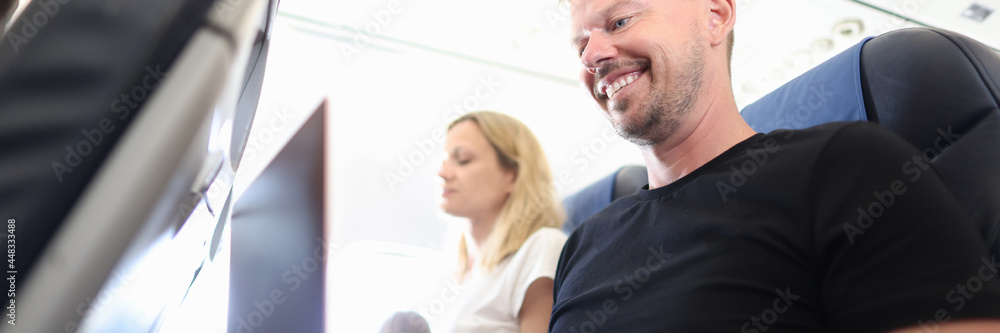 Man passenger flying in airplane and typing on laptop keyboard Man passenger flying in airplane and typing on laptop keyboard