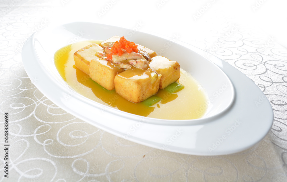 braised handmade bean curd tofu with crabmeat, luffa plant, roe in golden yellow sauce in white background asian halal menu braised handmade bean curd tofu with crabmeat, luffa plant, roe in golden yellow sauce in white background asian halal menu