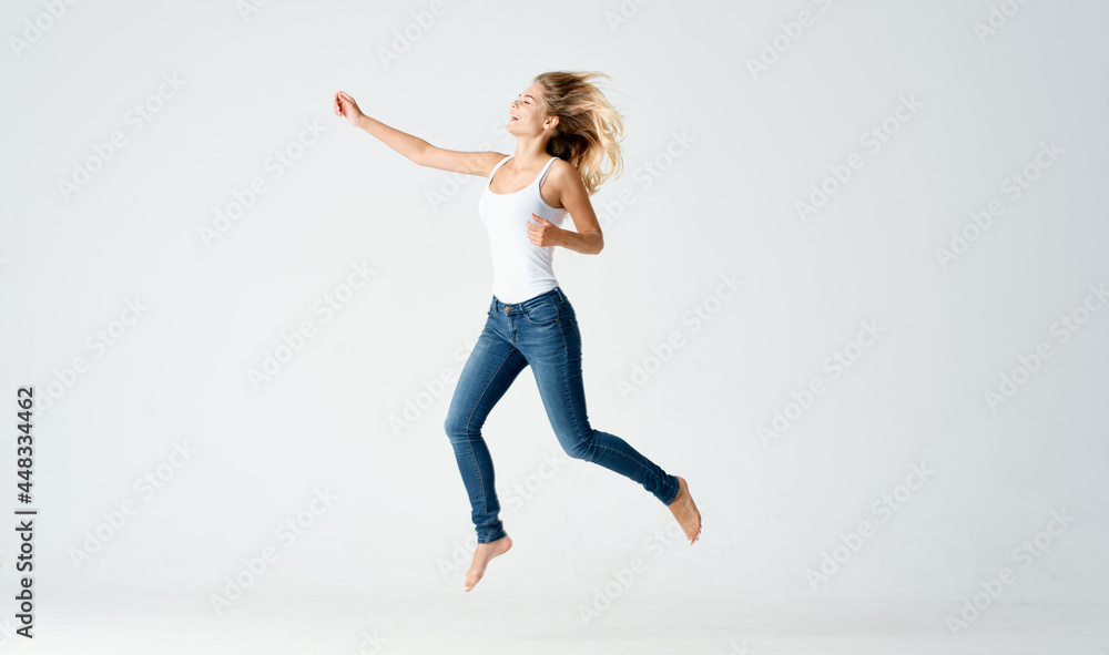 Fototapeta premium pretty woman in jeans movements dance barefoot light background
