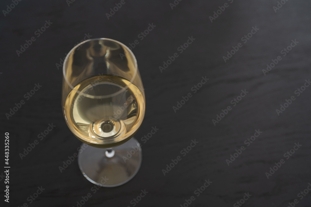 White wine in a wineglass on black oak table with copy space White wine in a wineglass on black oak table with copy space