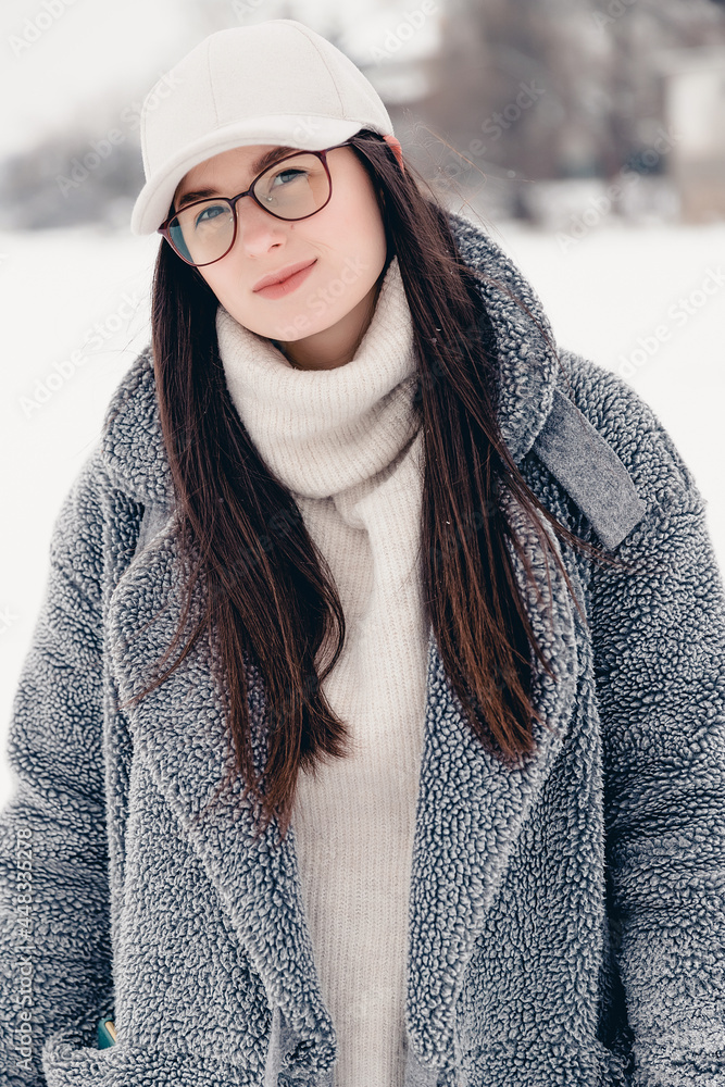 Portrait of an attractive girl dressed in stylish winter clothes. Woman posing for a photo on a snow-covered and icy lake in a local park Portrait of an attractive girl dressed in stylish winter clothes. Woman posing for a photo on a snow-covered and icy lake in a local park