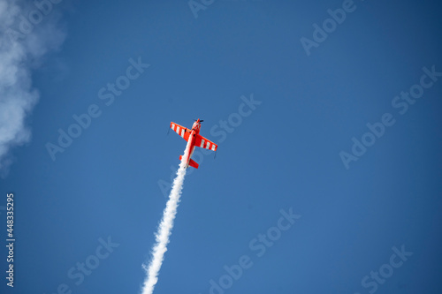 the red plane makes difficult turns and blows white smoke against the blue sky at the Max-21 aerospace salon in Zhukovsky on July 24, 2021 photo