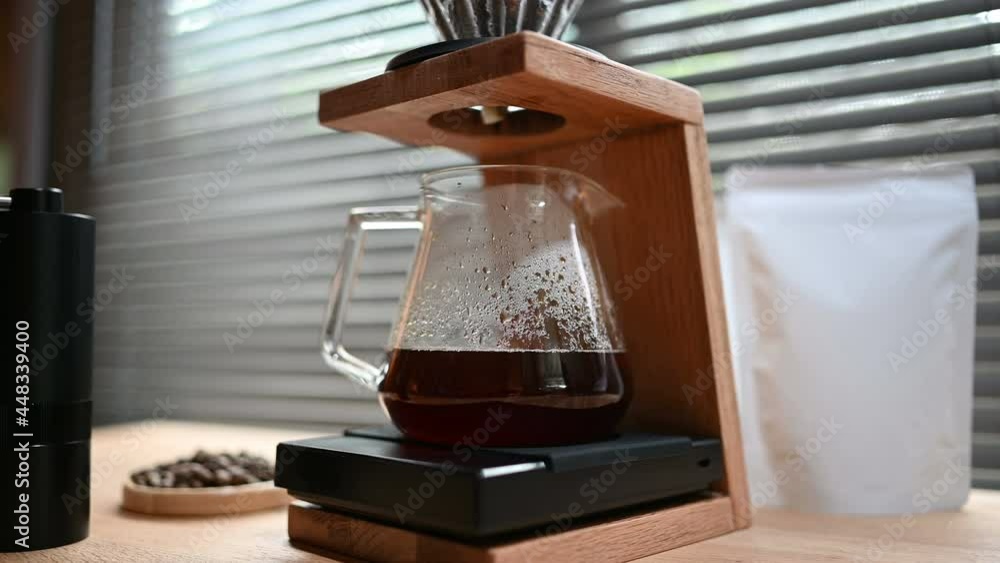 Close up hand drip coffee by spilling hot water through a layer of ground on the filter. Trendy drink brewed coffee dripping into a glass pot with blank coffee packaging for mockup. Close up hand drip coffee by spilling hot water through a layer of ground on the filter. Trendy drink brewed coffee dripping into a glass pot with blank coffee packaging for mockup.