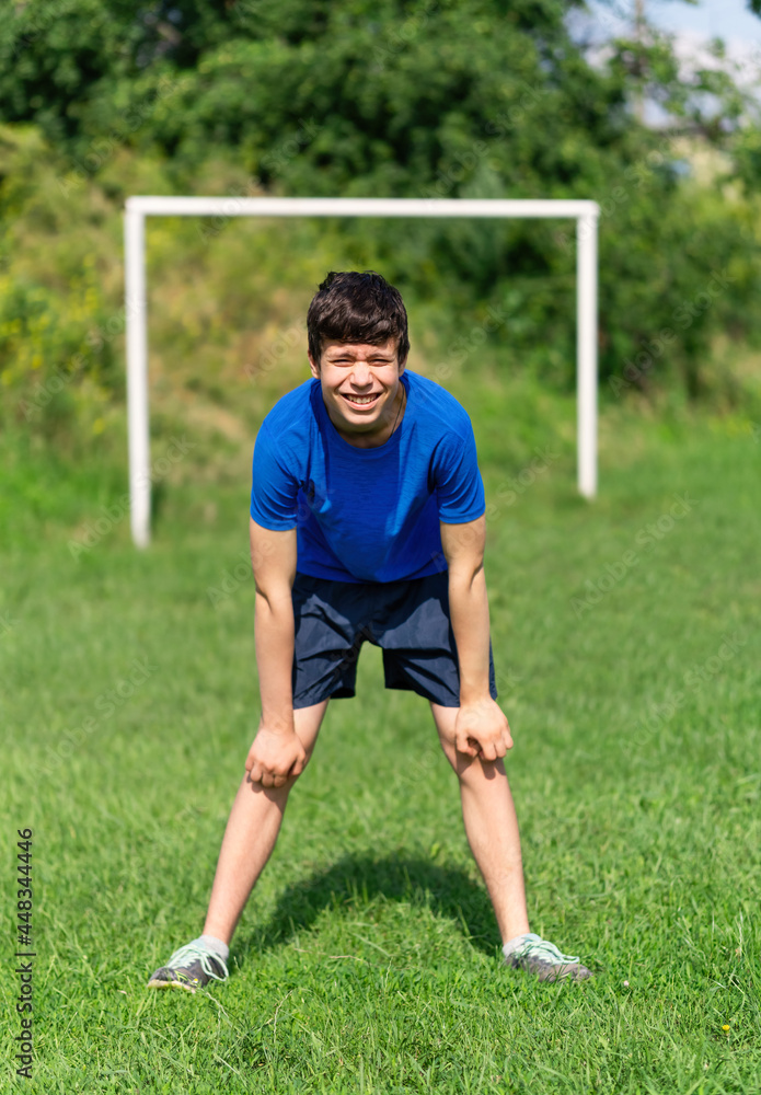 teenage boy exercising outdoors, sports ground in the yard, standing as a goalkeeper at the soccer gate, healthy lifestyle