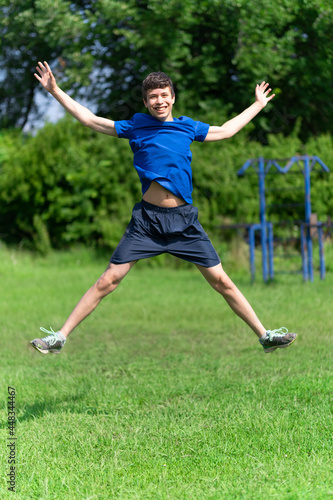teenage boy exercising outdoors, sports ground in the yard, he jumps high, healthy lifestyle
