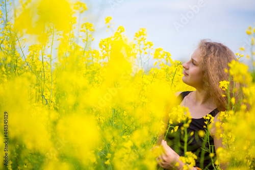 Blonde girl with luxurious long hair in a blooming rapeseed field of Ukraine