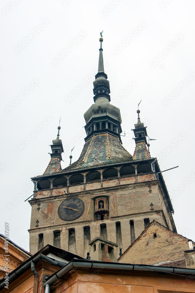 Clock on facade of derelict tower with steeple above, Sighisoara, Romania