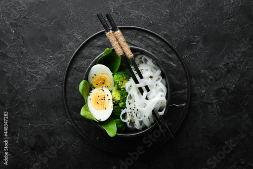 Rice noodles with egg, broccoli and spinach. Asian cuisine. Top view. Free space for your text.