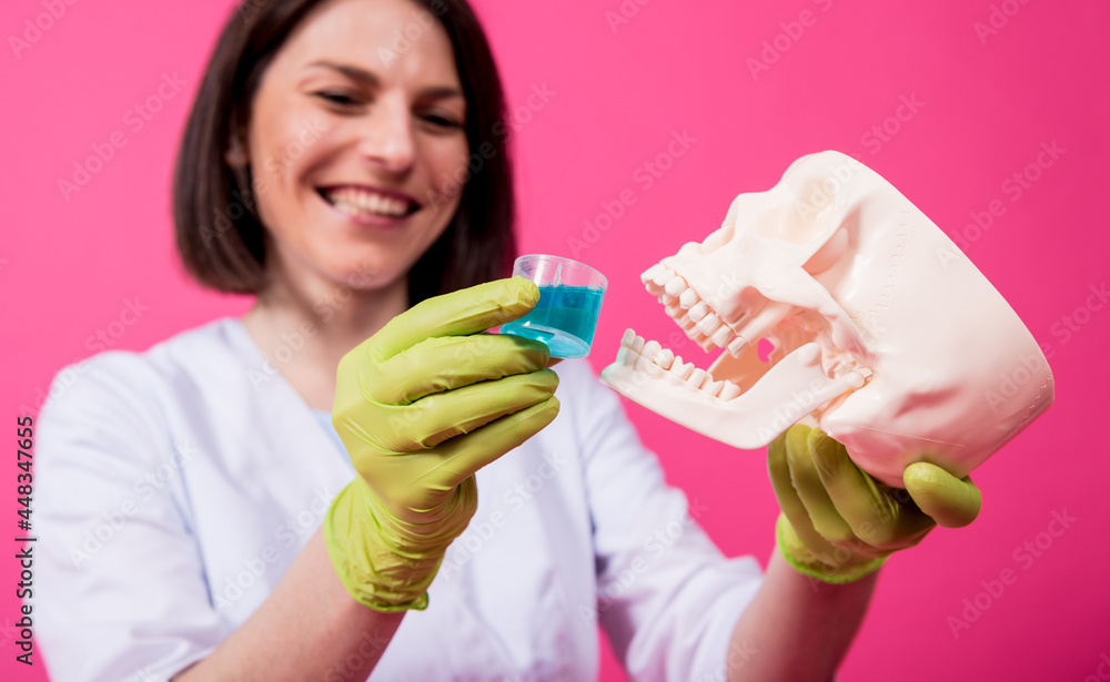 Beautiful girl proposes mouthwash for artificial skull Beautiful girl proposes mouthwash for artificial skull