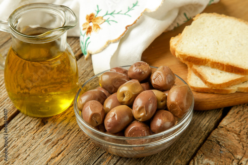 Olives, olive oil and bread on wooden rustic table.