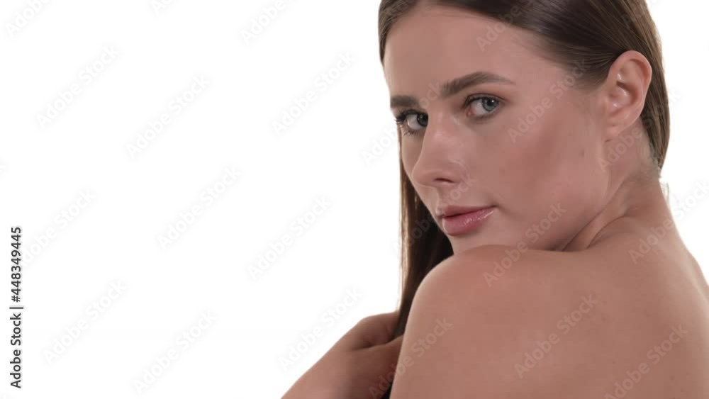 Close up of a beautiful Caucasian woman's face, shoulder and back, running her fingers through her silky, straight hair, looking at the camera, smiling. White background. Beauty concept. Close up of a beautiful Caucasian woman's face, shoulder and back, running her fingers through her silky, straight hair, looking at the camera, smiling. White background. Beauty concept.