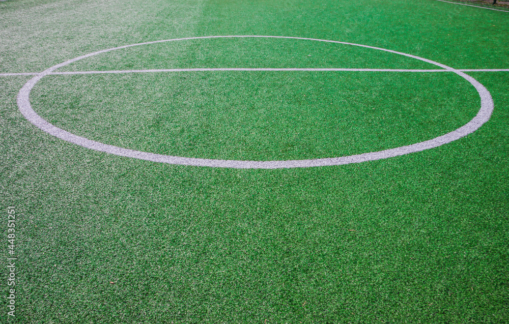 The centre of soccer field with artificial green grass and white lines near the school. Amateur football field. Sunny summer day