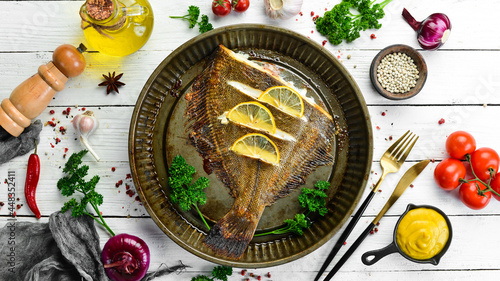 Photographie Baked flounder fish with lemon and spices on a metal baking dish