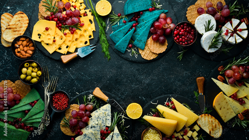 Cheese. Slices of cheese on plates: brie, blue, gorgonzola, parmesan and maasdam on a black stone background. Free copy space. Top view.