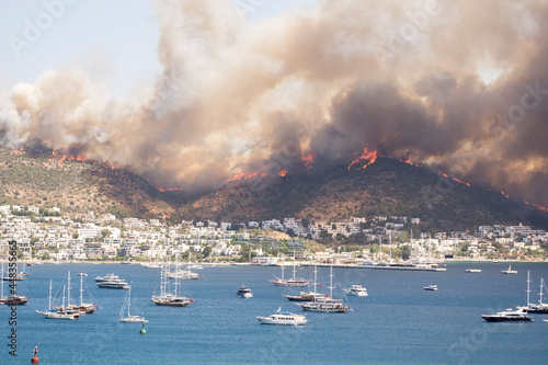 Breaking news: Flames and smoke from wildfires cover the landscape. Clouds of smoke from bush fire blew into the harbor of Bodrum, making it look like an apocalyptic landscape. Escaping to the sea