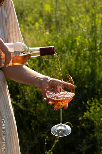 Woman pouring rose wine inro a glass in a summer garden photo