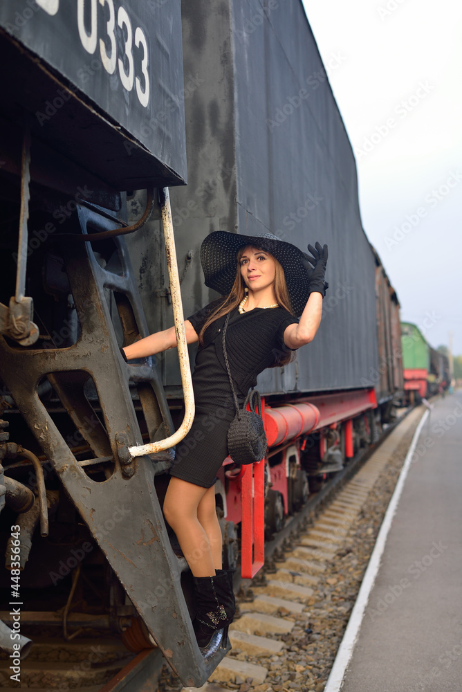 A woman in a black vintage dress on the old locomotive