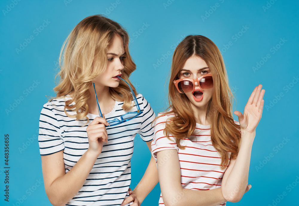 two girlfriends in striped t-shirts fashionable glasses entertainment glamor blue background two girlfriends in striped t-shirts fashionable glasses entertainment glamor blue background