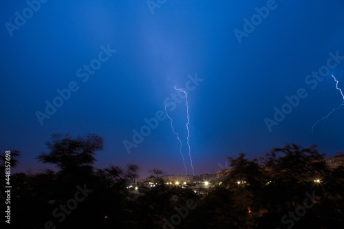 Lightning discharges during a large rainstorm in a city with forest fringes