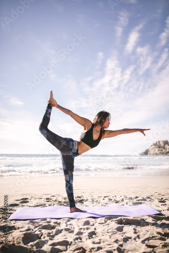 Woman doing Natarajasana yoga pose along the seashore photo