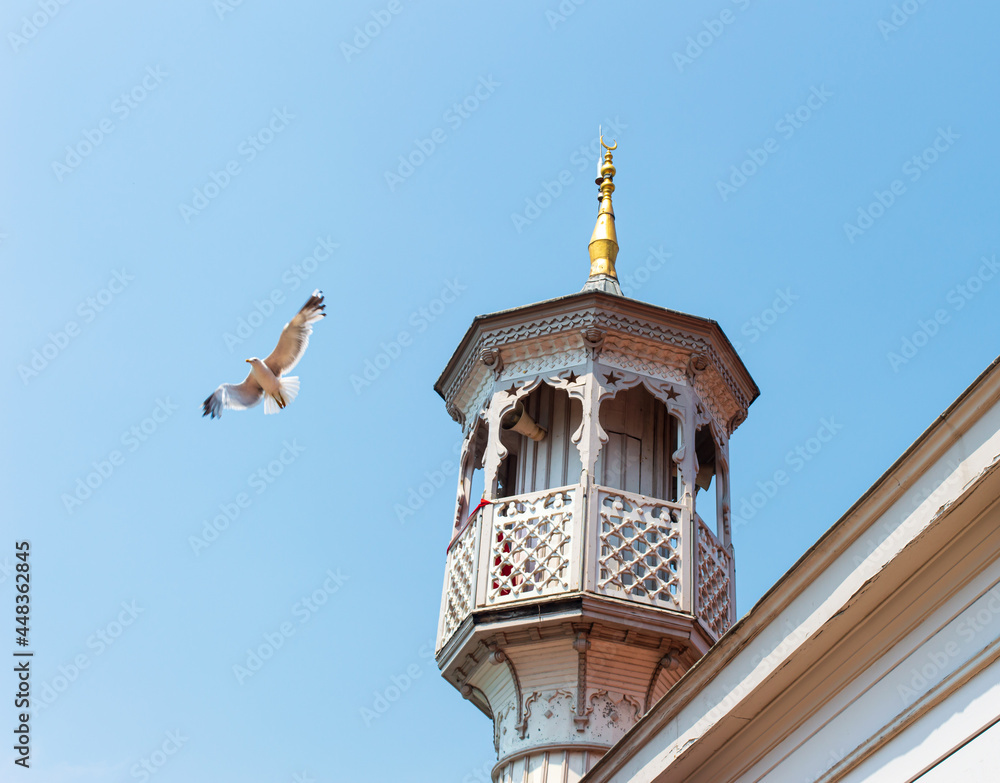 Minaret of a Muslim mosque with seagull on the clear blue sky background