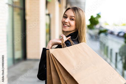 Beautiful woman holding shopping bags and smiling outdoors