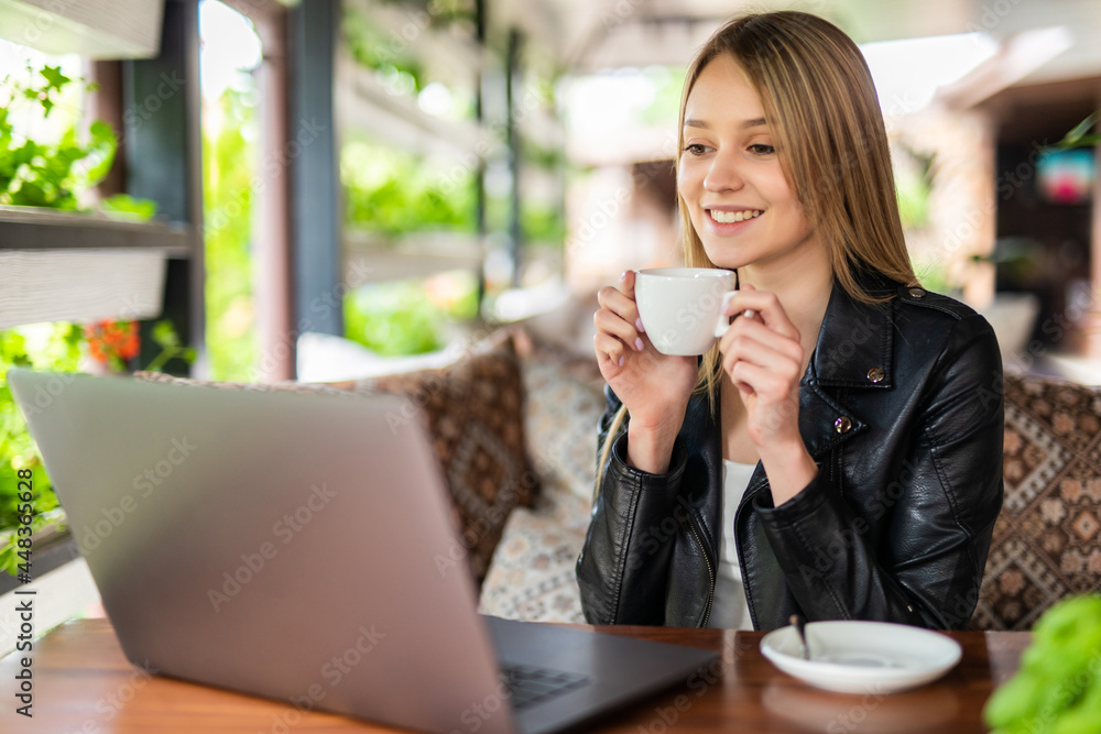 Beautiful brunette using notebook while drink coffee in cafe Beautiful brunette using notebook while drink coffee in cafe