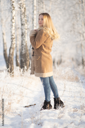 Beautiful girl in a frosty winter forest on a sunny day
