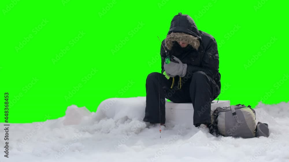 Fisherman with rod fishing in ice hole on green screen background . Ice hole for fishing . Shot on RED EPIC Cinema Camera Fisherman with rod fishing in ice hole on green screen background . Ice hole for fishing . Shot on RED EPIC Cinema Camera