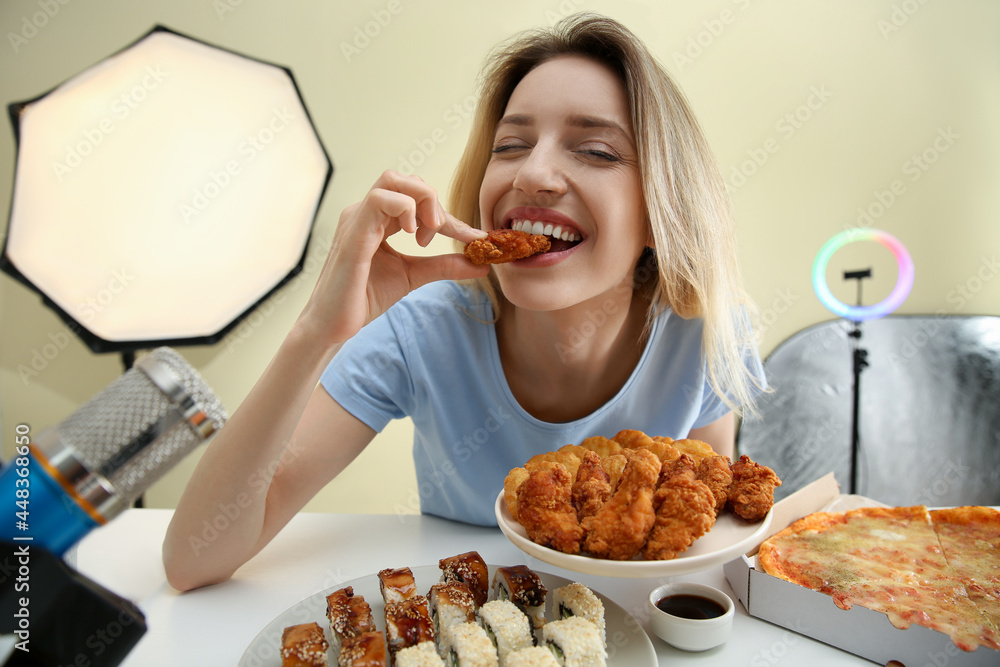 Food blogger eating in front of microphone at table against light background. Mukbang vlog Food blogger eating in front of microphone at table against light background. Mukbang vlog