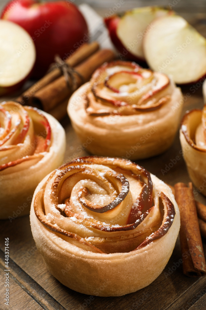 Freshly baked apple roses on wooden table, closeup. Beautiful dessert Freshly baked apple roses on wooden table, closeup. Beautiful dessert