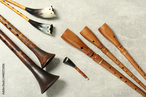 Vintage zhaleikas and bryolkas on light grey background, flat lay. Woodwind musical instruments