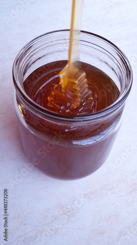 honey flowing into a glass jar on a light background